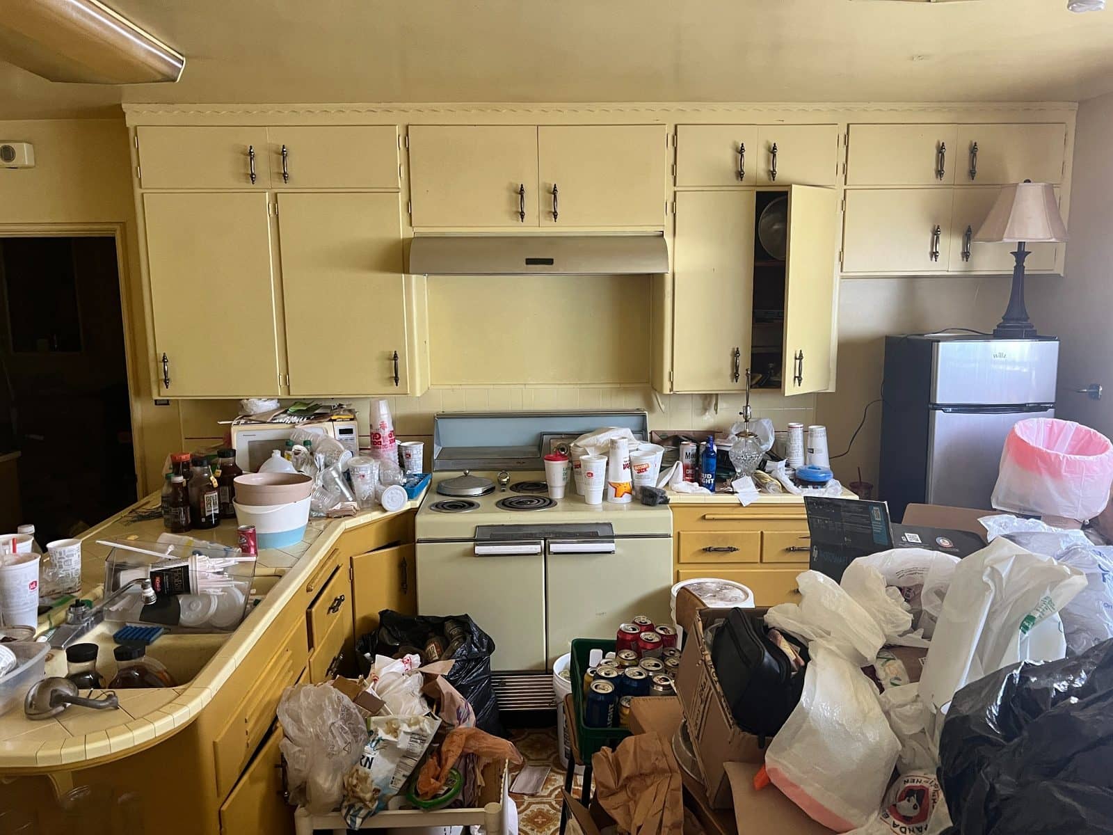 A dated kitchen we purchased as-is, with belongings still covering the counters.